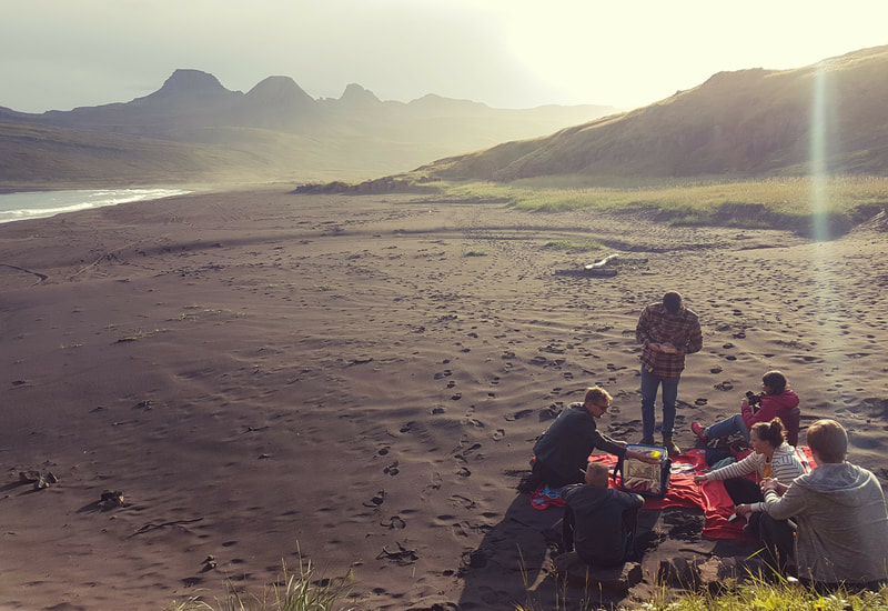 A family is having a picnic on the black sand beach in Vöðlavík. 