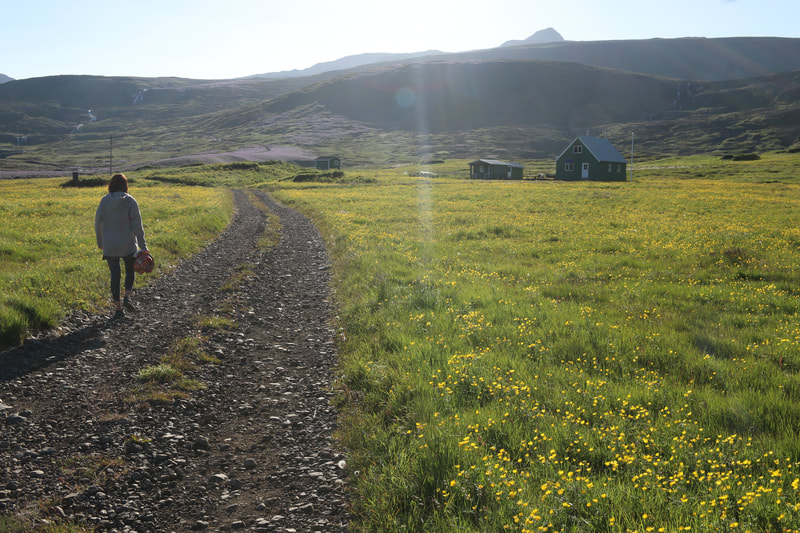 A girl walks along an old gravel road towards the travelers' hut in Vöðlavík. 