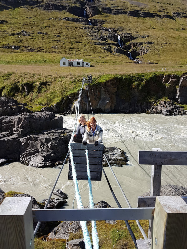 Two women crossing a glacier river in an old Icelandic cable bridge that is near the Wilderness Center in Fljótsdalur. 