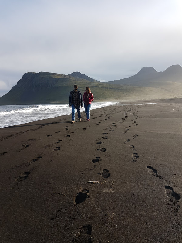 A man and woman walking along the shore in Vöðlavík