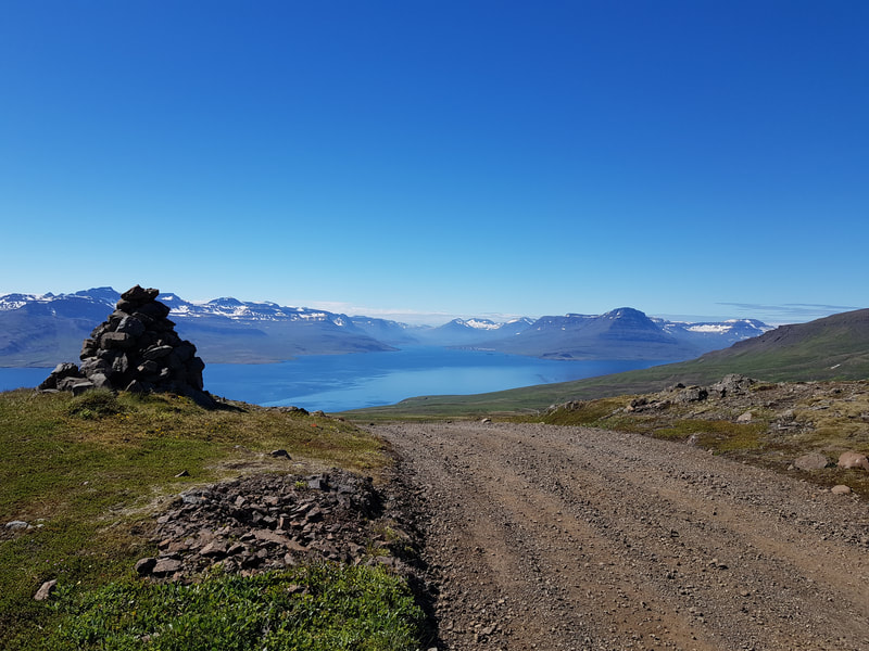 A cairn by the gravel road to Vöðlavík. In the background is the ocean. 