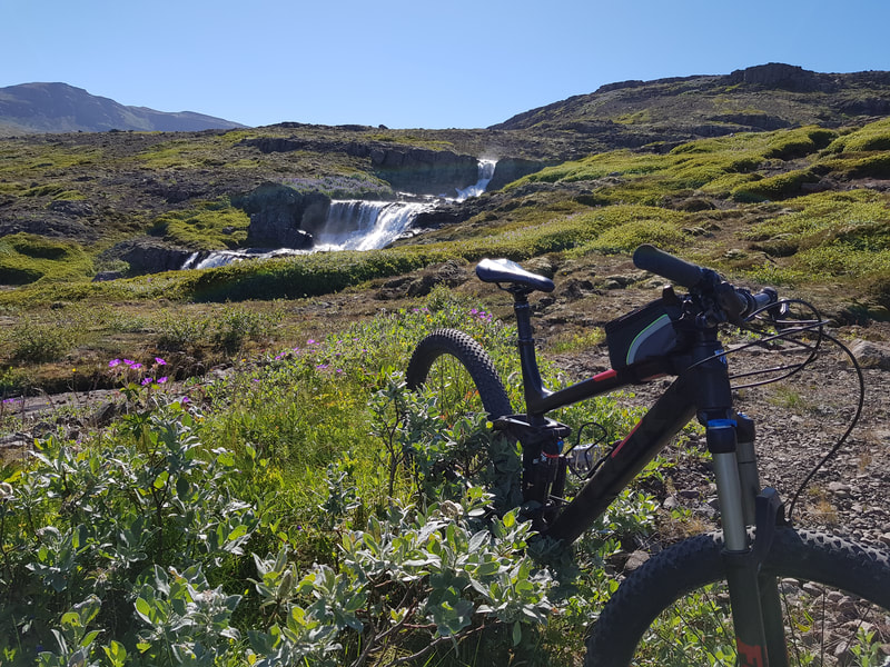 A bike, the lush hillside and a waterfall in the distance. 