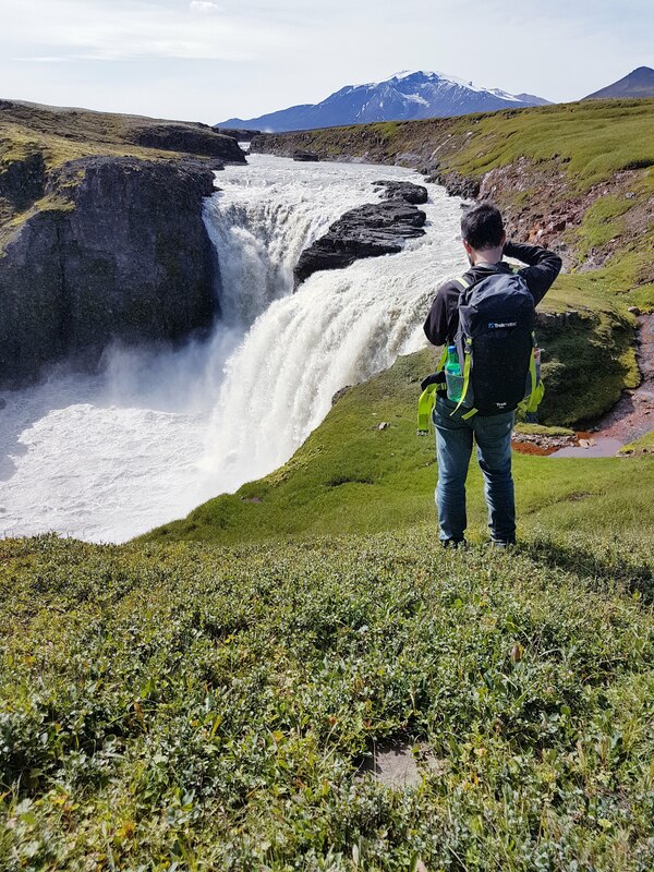 A traveler takes a photo of a waterfall on the hiking path the waterfall circle in the highlands above Fljótsdalur. 