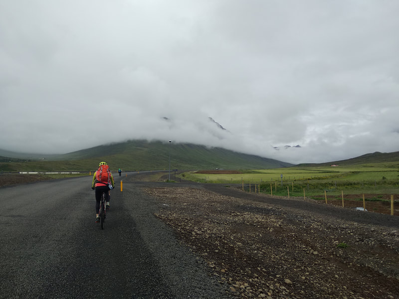 A woman biking on the road from Neskaupsstaður. 
