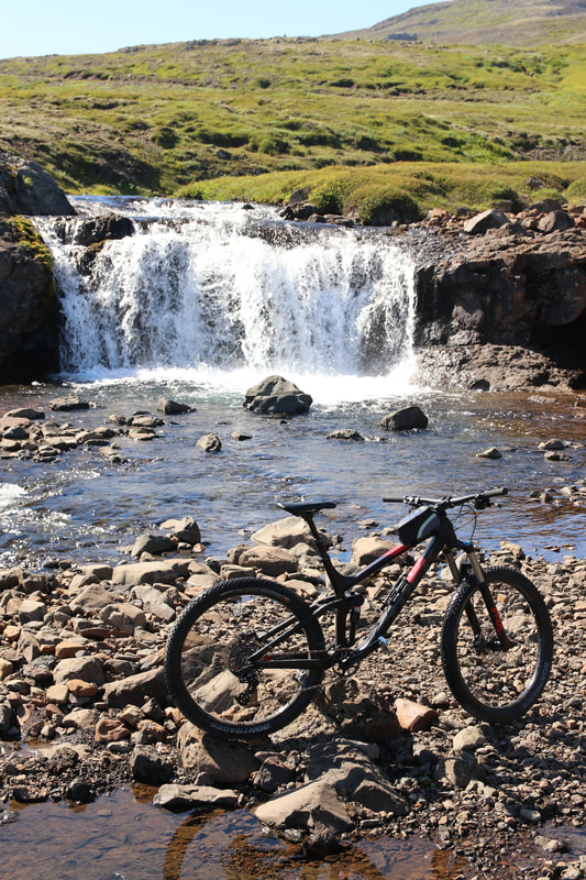 A mountain bike parked in front of a small waterfall. 