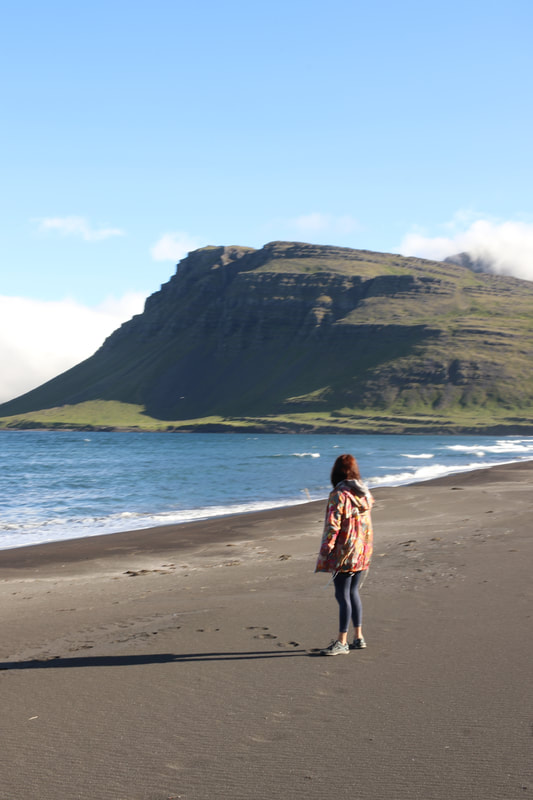 A girl standing on the black sand beach in Vöðlavík. 