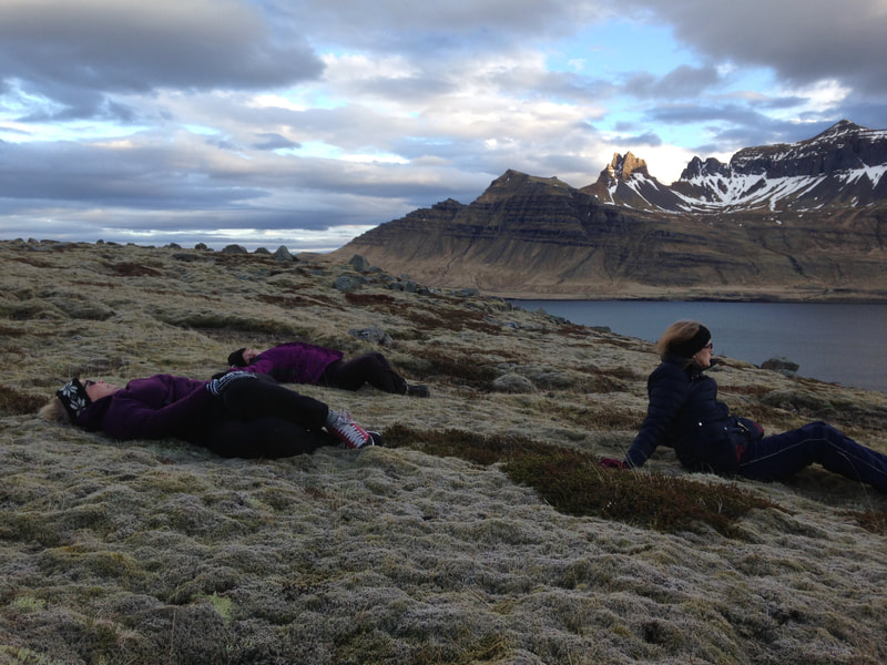 Three women sitting or lying in the hillside above Stöðvarfjörður. 