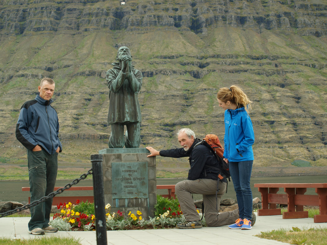 A local guide in Eskifjörður with two guests by the memorial of fishermen who drowned. 